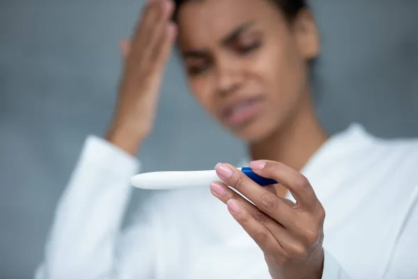 Unhappy frustrated young african ethnic woman holding pregnancy test. — Stock Photo, Image