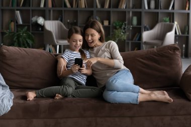 Annesi evde akıllı telefon kullanan mutlu, tatlı bir kız çocuğu.