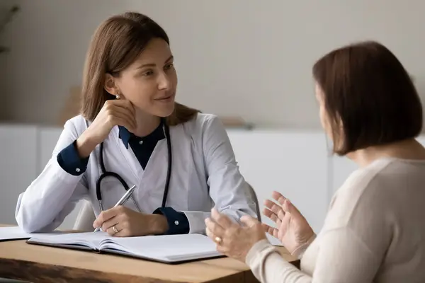Женщина-врач-терапевт слушает взрослую женщину-пациента на встрече — стоковое фото