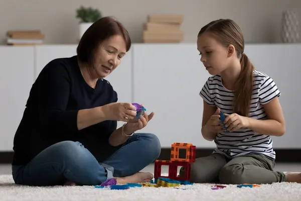 Soins mature grand-mère et petite fille jouer avec des jouets ensemble — Photo