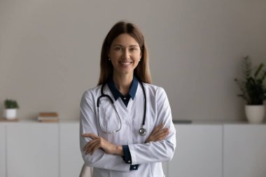 Kollarını kavuşturmuş gülümseyen kadın doktor portresi.