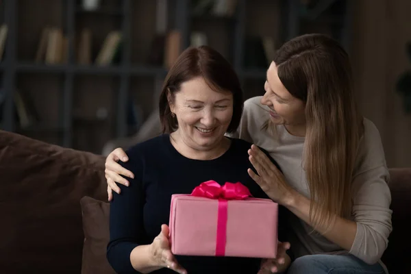 Amar a la hija adulta felicitando a la madre madura, presentando caja de regalo —  Fotos de Stock