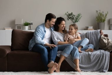 Mutlu ebeveynler ve kızı evdeki rahat koltukta dinleniyorlar.