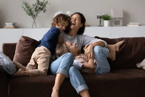 Overblij moeder met twee kinderen hebben plezier op comfortabele bank — Stockfoto