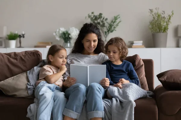 Smiling mother reading book to adorable little kids at home — Stock Photo, Image