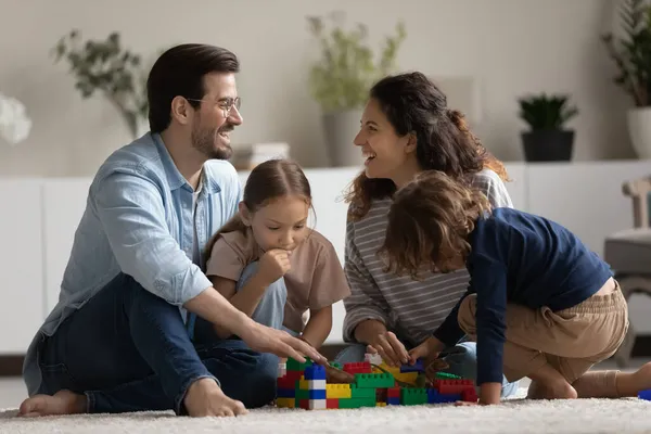 幸せな両親と2人の子供が床でおもちゃで遊んでいます — ストック写真