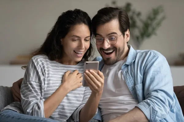 Взбудораженная пара смотрит на экран смартфона, читает новости — стоковое фото