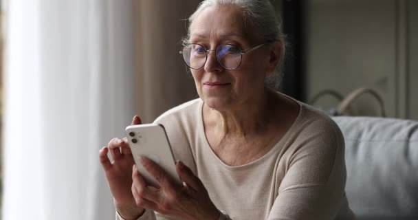 Lachen volwassen oma chatten met kleinkind online met behulp van telefoon — Stockvideo