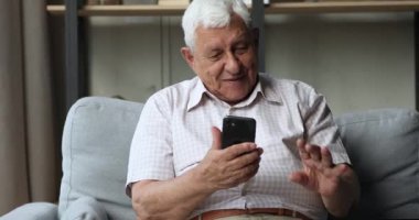 Mutlu yetişkin büyükbaba akıllı telefondan sevgili torunlarına video görüşmesi yapıyor.