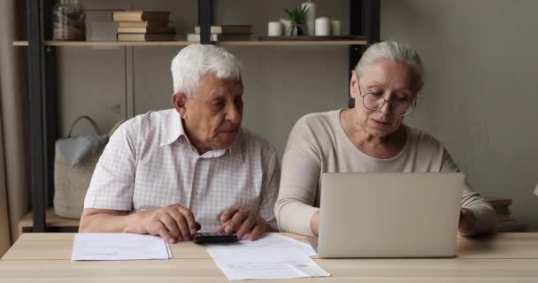 Gericht volwassen echtgenoten doen huishoudelijk papierwerk met behulp van rekenmachine en laptop — Stockvideo