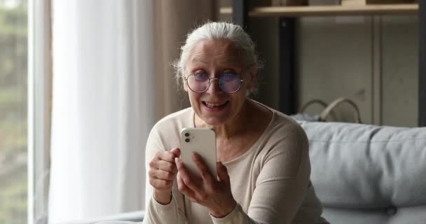Przepełniony radości starszy kobieta porozmawiać przez videocall na nowoczesnym telefonie — Wideo stockowe