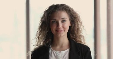 İçeride poz veren uzun kıvırcık sarı saçlı güzel bir genç kadın.