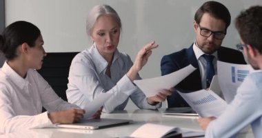 Çeşitli iş adamları satış sonuçlarını, grafikleri ve istatistikleri tartışıyor