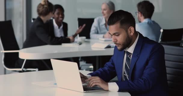 Allvarligt fokuserad indisk entreprenör sitta vid skrivbordet arbetar på bärbar dator — Stockvideo