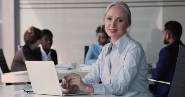 Orta yaşlı güzel bir iş kadınının portresi dizüstü bilgisayarla masada oturuyor. — Stok video