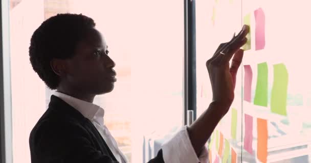 严肃的非洲女商人站在办公室里贴着便条 — 图库视频影像