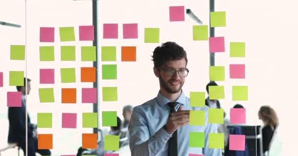 Hombre empleado anotando información y recordatorios en pegatinas post-it — Vídeo de stock