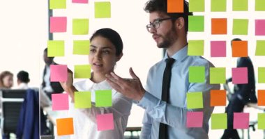 Yapışkan notlar kullanarak görevleri ve fikirleri belirleyen çok ırklı meslektaşlar