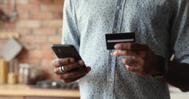 Elinde kart olan Afrikalı adam ve akıllı telefon internet üzerinden alışveriş yapıyor