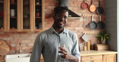 Elinde durgun su bardağı tutan Afrikalı adam baş parmağını kaldırıyor.