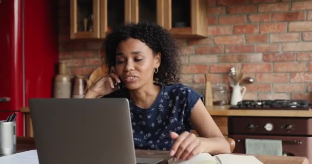 Afrikaanse freelancer vrouw met behulp van laptop praten op smartphone — Stockvideo