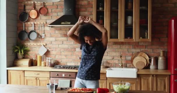 Mujer africana feliz bailando mientras cocina en la cocina moderna — Vídeos de Stock