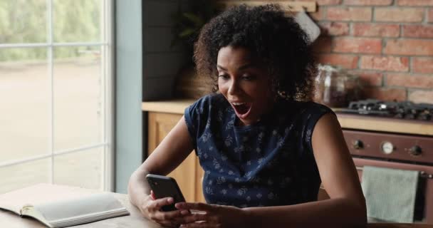 Mujer africana sostiene teléfono celular leer noticias increíbles se siente feliz — Vídeo de stock