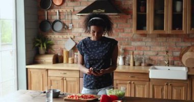 Kulaklık takan Afrikalı kadın cep telefonu uygulaması kullanıyor.