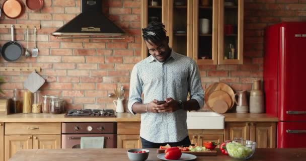 African guy holding smartphone search wegetariańskie przepisy kulinarne korzystać online app — Wideo stockowe