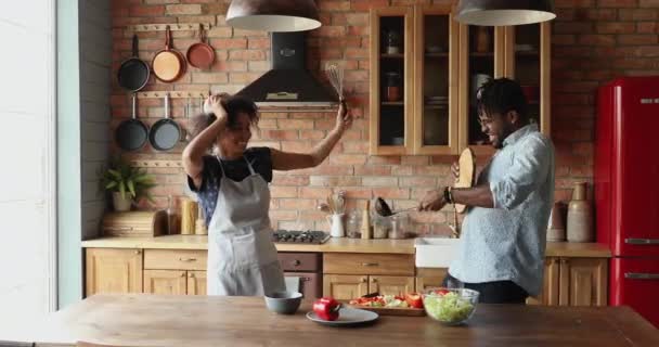 Afrikalı çift mutfakta mutfak gereçleri savaşırken eğleniyor. — Stok video