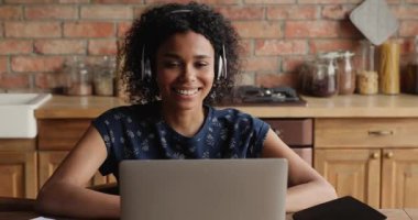Kulaklık takan çekici Afrikalı kadın laptopta video çağrısı yapıyor.