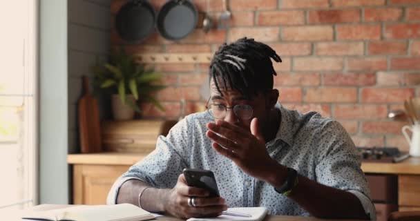African man holds smartphone reading message feels stressed looks upset — Stock Video