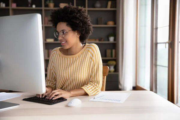 Gelukkig jong zwart student meisje in bril werken op desktop — Stockfoto