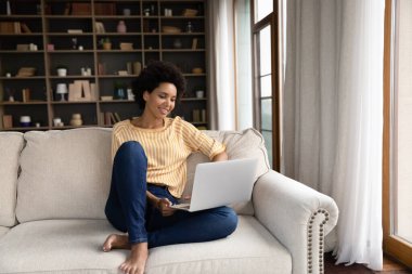 Gülümseyen siyah kadın dizüstü bilgisayar kullanıyor.