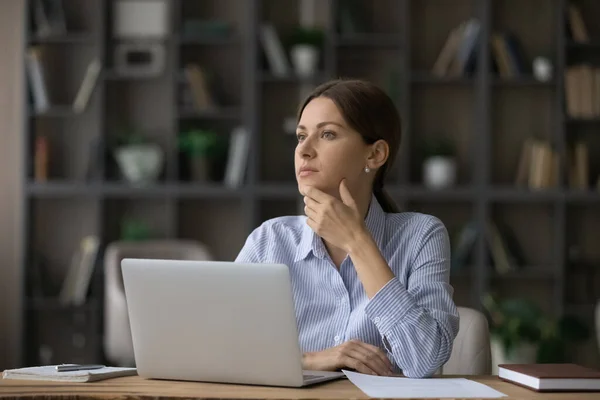 Mujer atractiva profunda en pensamientos sentarse en el lugar de trabajo cerca de la computadora portátil — Foto de Stock