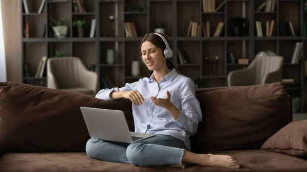 Kadın kanepeye oturur video konferansı boyunca dizüstü bilgisayar kullanır. — Stok fotoğraf