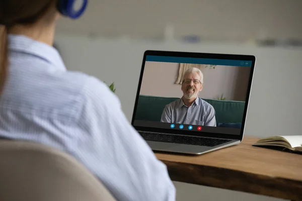 Achteraanzicht vrouw dragen hoofdtelefoon praten met vader via videocall — Stockfoto
