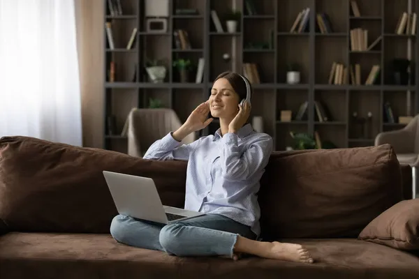 Mulher ouvir música através de fones de ouvido usando serviços de streaming no laptop — Fotografia de Stock