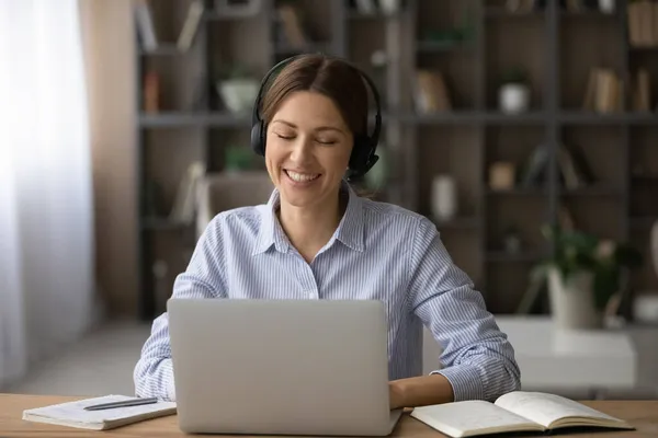 Vrouw met een headset kijkt naar laptop scherm genieten van communicatie op afstand — Stockfoto