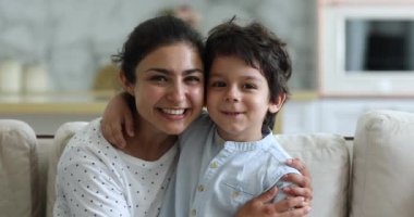 Hintli anne ve anaokulu çocuğu kucaklaşıp kameraya bakın.
