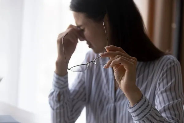 Mujer joven agotada quitándose las gafas, teniendo la vista borrosa. — Foto de Stock