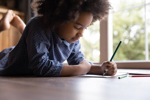 Счастливая очаровательная маленькая афроамериканская девочка рисует картинки.