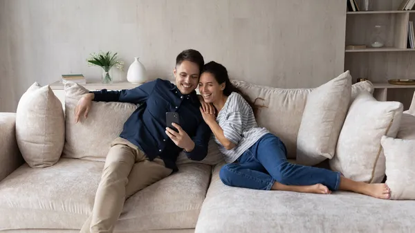 Couple relaxing indoor having fun watch funny videos on cellphone — Stock Photo, Image