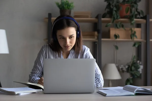 Happy young woman in headphones watching educational lecture on computer. — Stock Photo, Image