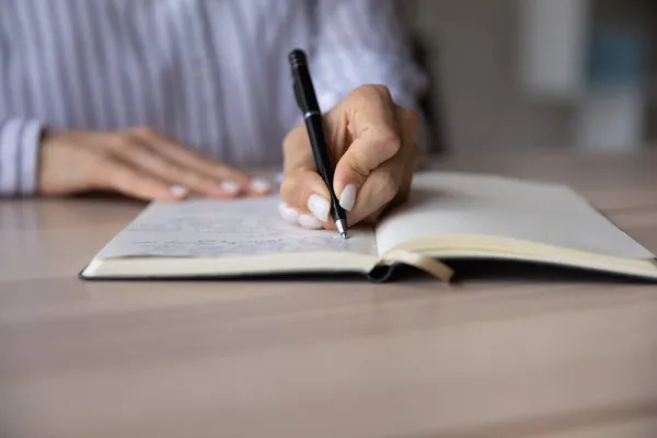 Primer plano joven mujer de negocios notas de escritura a mano en planificador de papel. —  Fotos de Stock