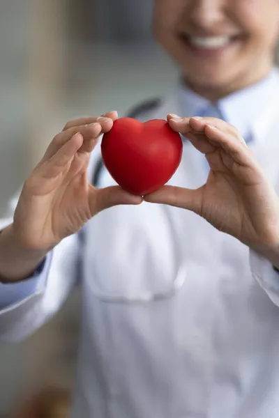 Vertical de cerca sonriente india médico sosteniendo el corazón — Foto de Stock