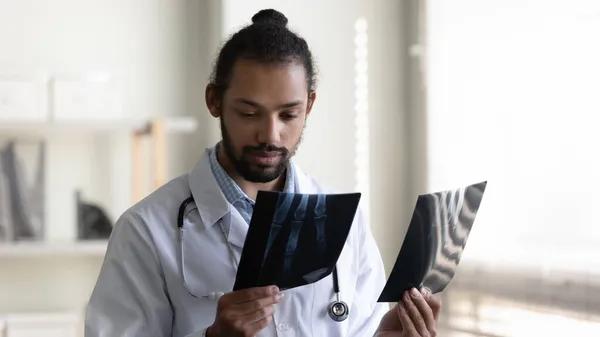 Médico afroamericano serio sosteniendo imágenes de rayos X — Foto de Stock