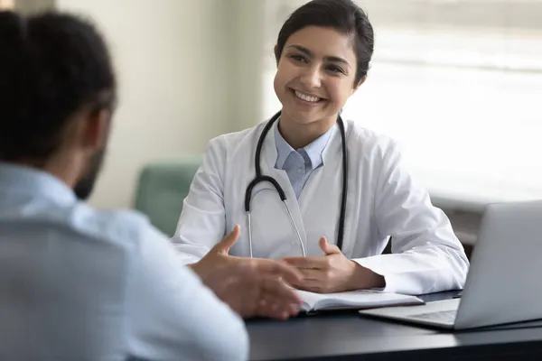 Sorrindo jovem indiana médico consultando paciente afro-americano — Fotografia de Stock