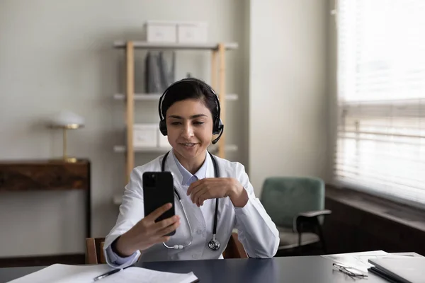 Sonriente mujer india médico en auriculares con teléfono inteligente, hablando — Foto de Stock