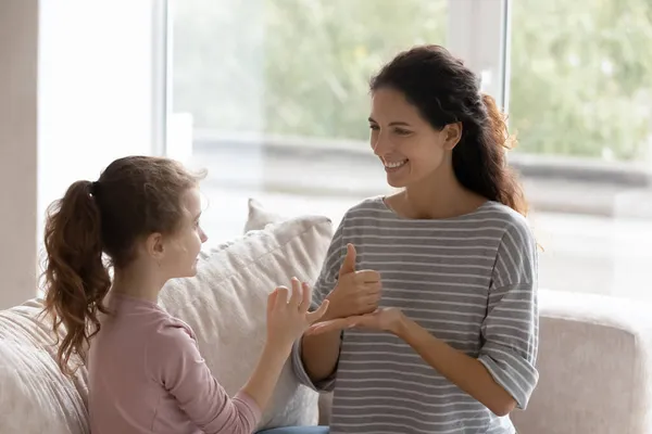 Leende omtänksam mor undervisar handikappad dotter, inlärningstecken gest — Stockfoto